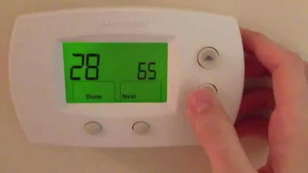 a man resetting honeywell thermostat